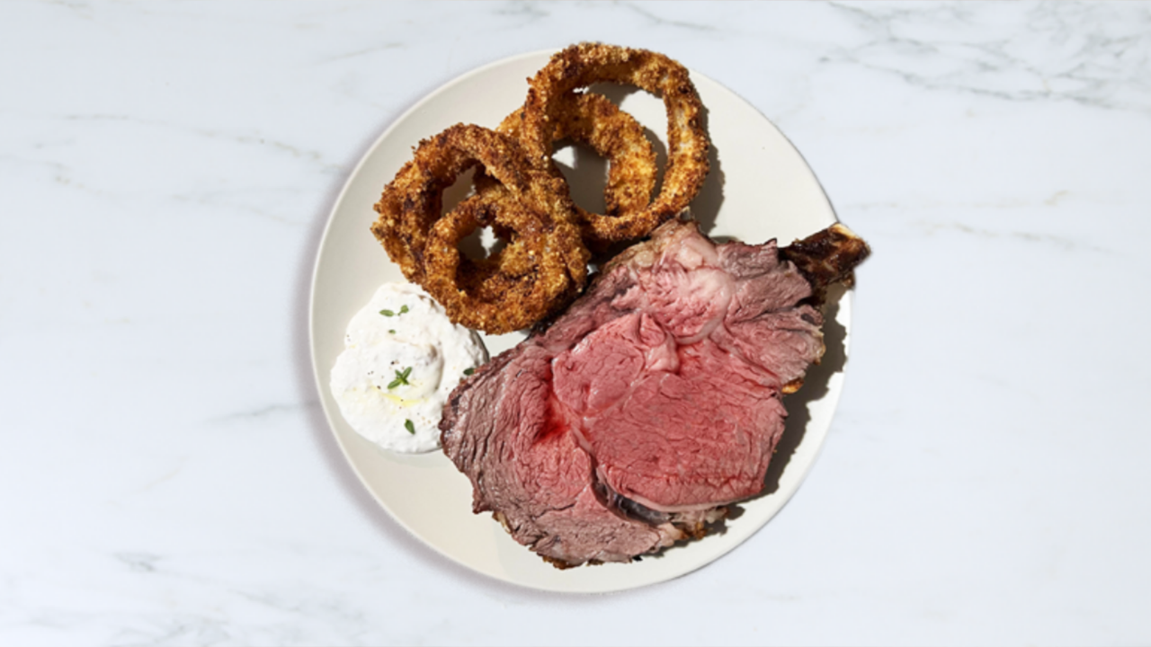 Plate of prime rib, onion rings, and sauce