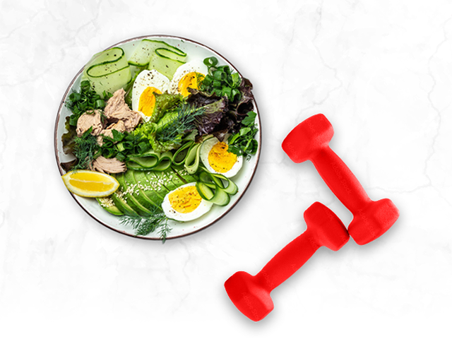 Salad with hard boiled egg, cucumber, avocado, chicken, lemon slice, and a set of two dumbbells